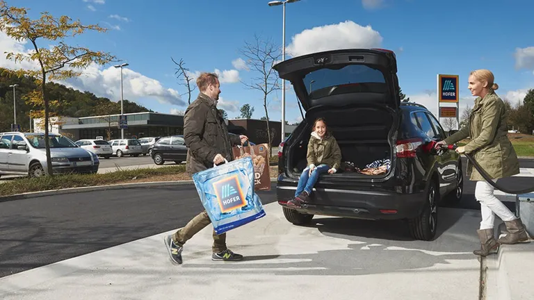 Family filling up the car with gas and loading shopping bags into it.